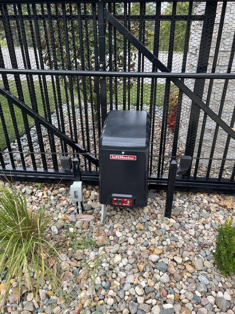 A LiftMaster gate operator installed on a black metal fence by Brothers Gate Operators and Services LLC in Olathe, KS.