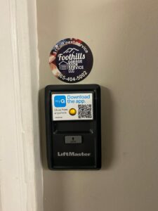 A LiftMaster smart garage door wall control with a QR code and Foothills Garage Door Service LLC sticker in Louisville, TN.