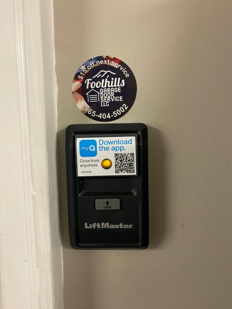 A LiftMaster smart garage door wall control with a QR code and Foothills Garage Door Service LLC sticker in Louisville, TN.