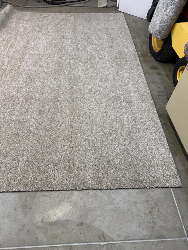 A light beige carpet piece laid on a concrete floor, ready for or after binding by Rug Edge Binding Company in Spokane, WA