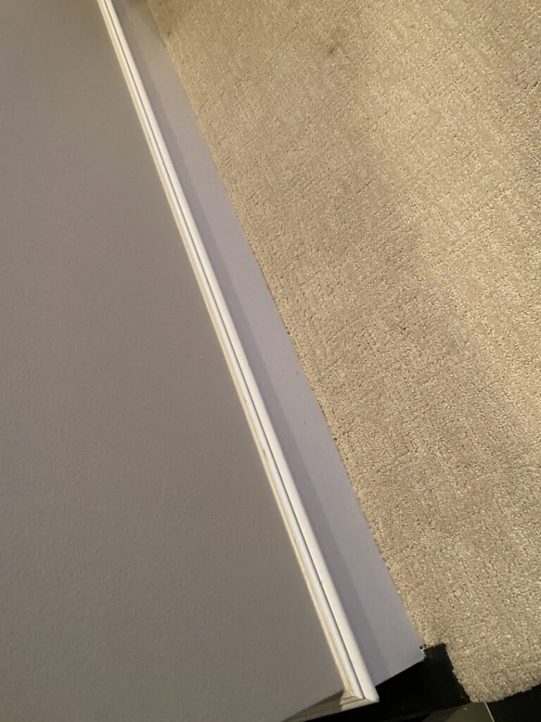 Newly installed light-colored carpet neatly fitted against a white wall by Floor Gallery in Pearland, TX