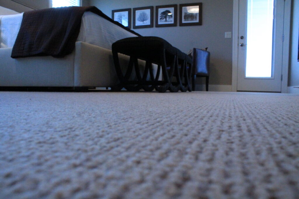 A close-up view of light-colored, textured carpet installed in a bedroom by Rich's Modern Flooring in Billings, MT.