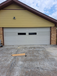 A light-colored garage door with two rectangular windows installed by Residential WorX LLC in Westlake, LA.