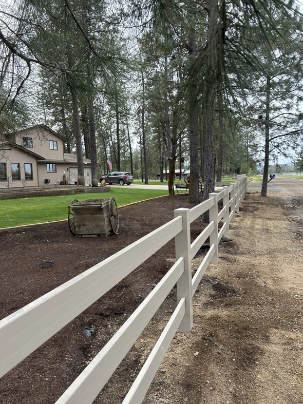 A light-colored multi-rail ranch-style fence installed along a property line by BKC Fencing in Spokane, WA.