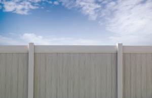 A close-up of a light-colored vinyl privacy fence with textured panels, installed by Performance Fencing in Rigby, ID.