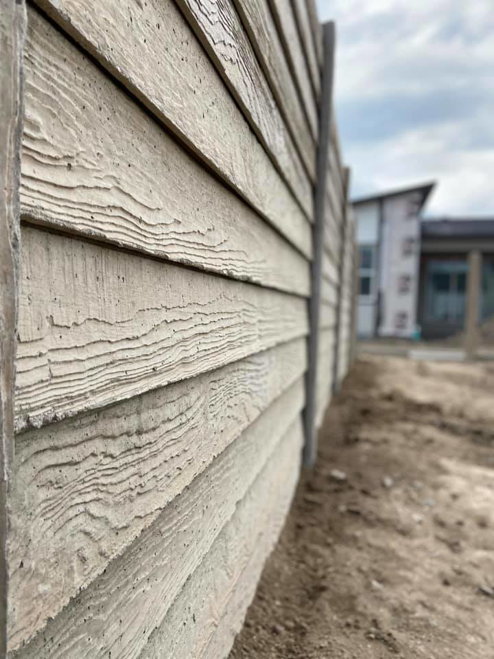 A close-up of a light-colored concrete fence with a wood grain texture installed by BroKrete Fencing LLC in Salt Lake City, UT