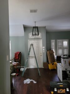 A new light fixture being installed or replaced from a ladder, showing electrical work by Quistian Lighting in Arlington, TX