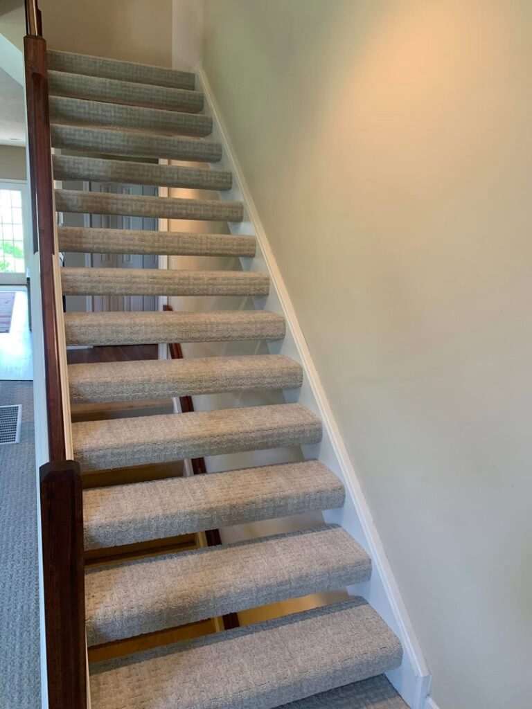 A clean light gray carpet runner installed on a staircase by Garrard's Flooring Service LLC, a carpet contractor in Cleveland, OH.