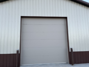 A light grey commercial garage door on a two-tone building by Usa Garage Door Services and Construction, LLC at 1206 E 6th St, USA.