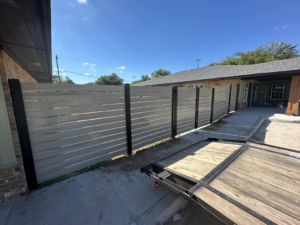 A light grey composite fence installed at a residential property by Goliath Fence Systems and Pre-Stain in Oklahoma City, OK.