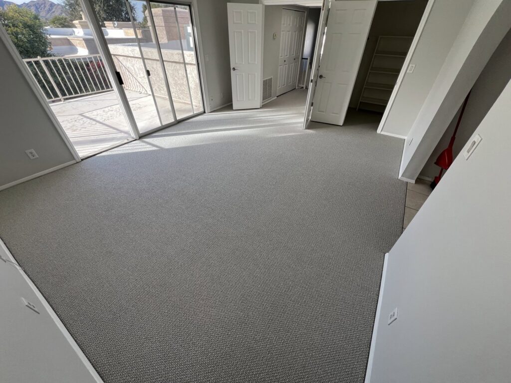 A bedroom featuring a new light grey patterned carpet installation by Canyon State Flooring in Queen Creek, AZ.
