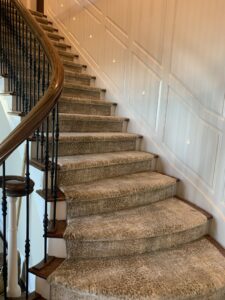 A light leopard print carpet runner expertly installed on a curved staircase by The Carpet Workroom in Needham Heights, MA.