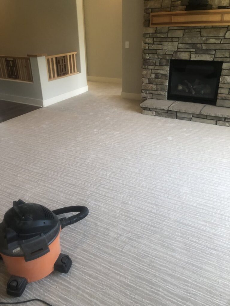 A light-colored, textured carpet in a living room with a shop vacuum, indicating recent work by Grand Rapids Flooring in Grand Rapids, MI.