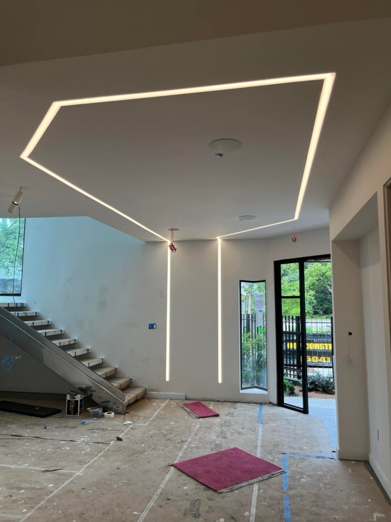 Modern linear LED lighting installed in the ceiling and walls of a room under construction by Krajcer Electric in New Orleans, LA