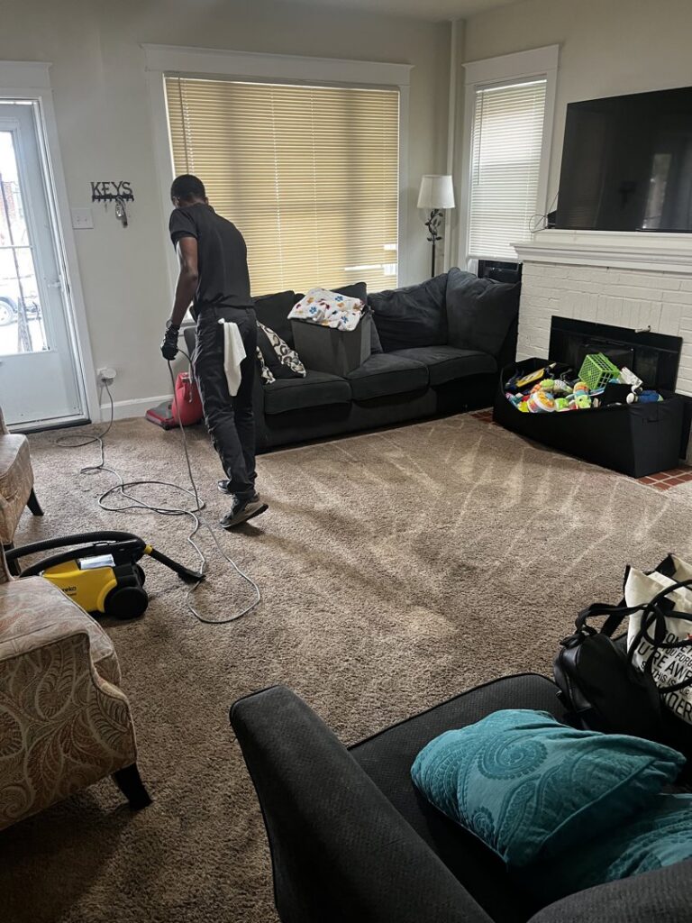 An LHB Clean Team technician cleaning a living room carpet with professional equipment in Harrisburg, PA.