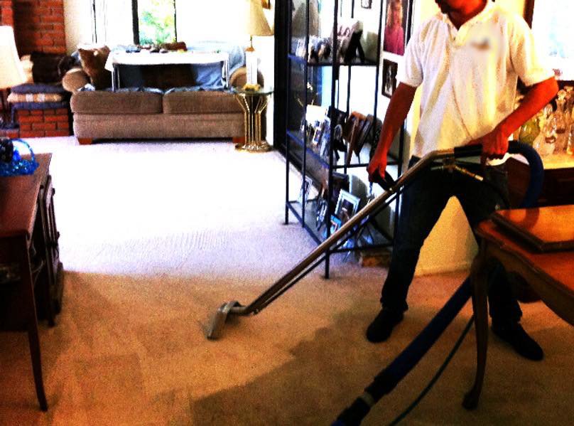 A professional cleaning a living room carpet with specialized equipment by Mexsteam in San Diego, CA