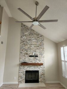 A living room with a newly installed ceiling fan above a fireplace by ALC Electric LLC in Goose Creek, SC