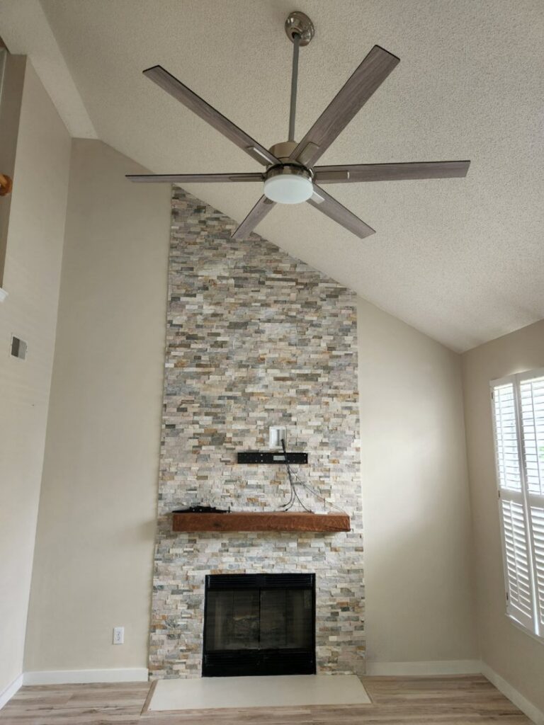 A living room with a newly installed ceiling fan above a fireplace by ALC Electric LLC in Goose Creek, SC