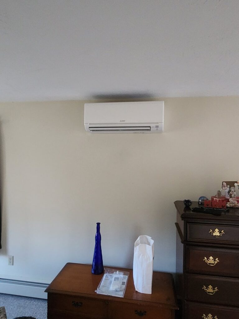A white mini-split air conditioning unit installed on a living room wall by C & C Temp Control in Worcester, MA.