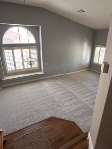 A large living room with freshly installed gray carpet, showing vacuum lines, by Floors by Aldaba LLC in North Las Vegas, NV.