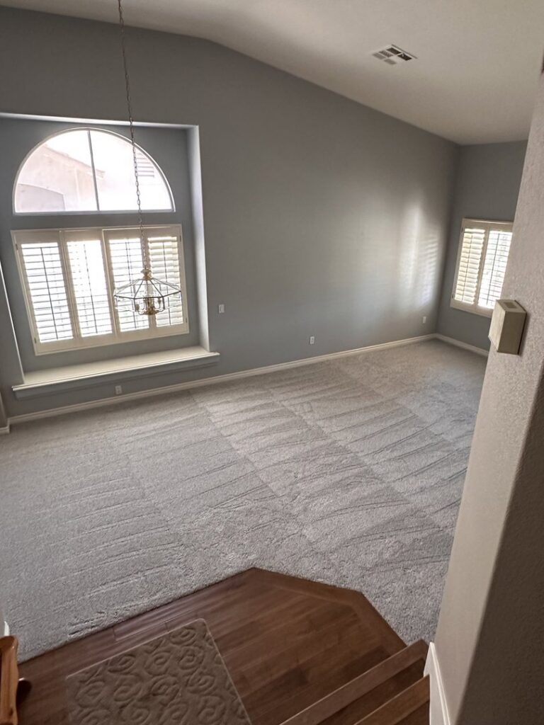 A large living room with freshly installed gray carpet, showing vacuum lines, by Floors by Aldaba LLC in North Las Vegas, NV.