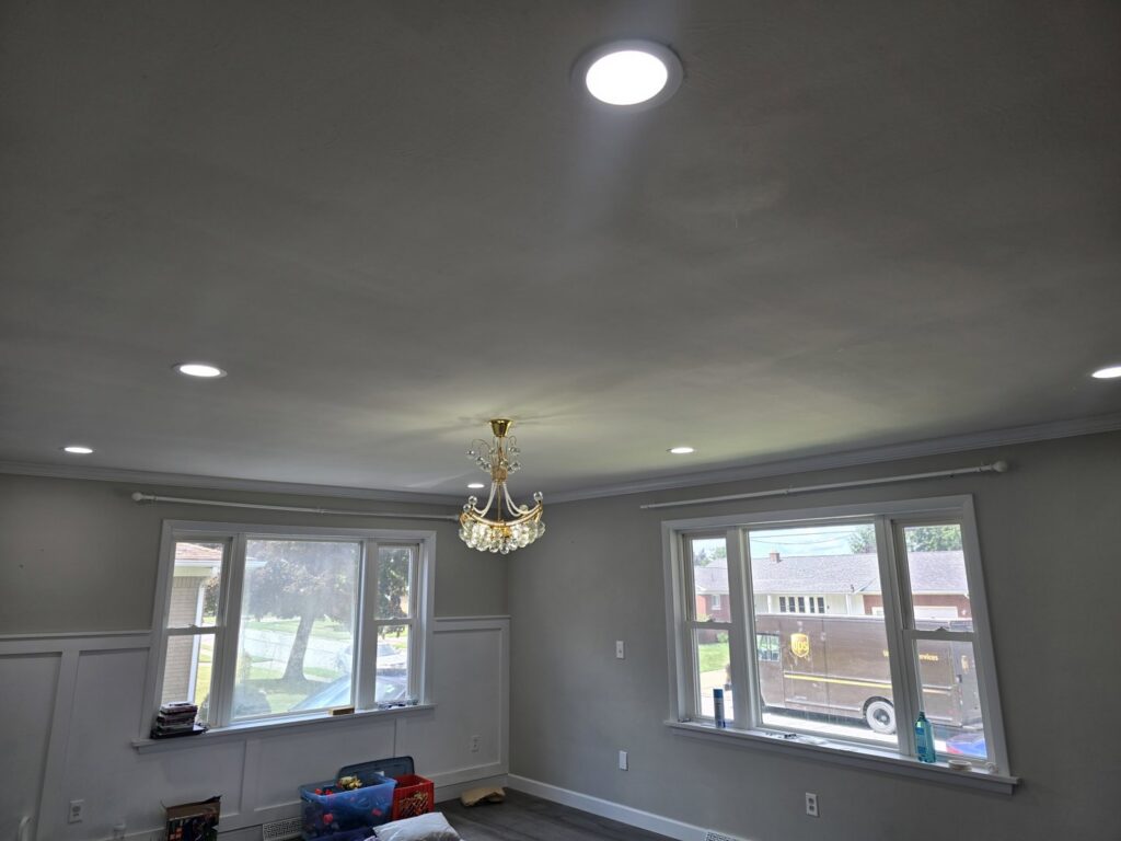 A living room featuring new recessed lighting and a chandelier installed by Be Bright Electric in Erie, PA.