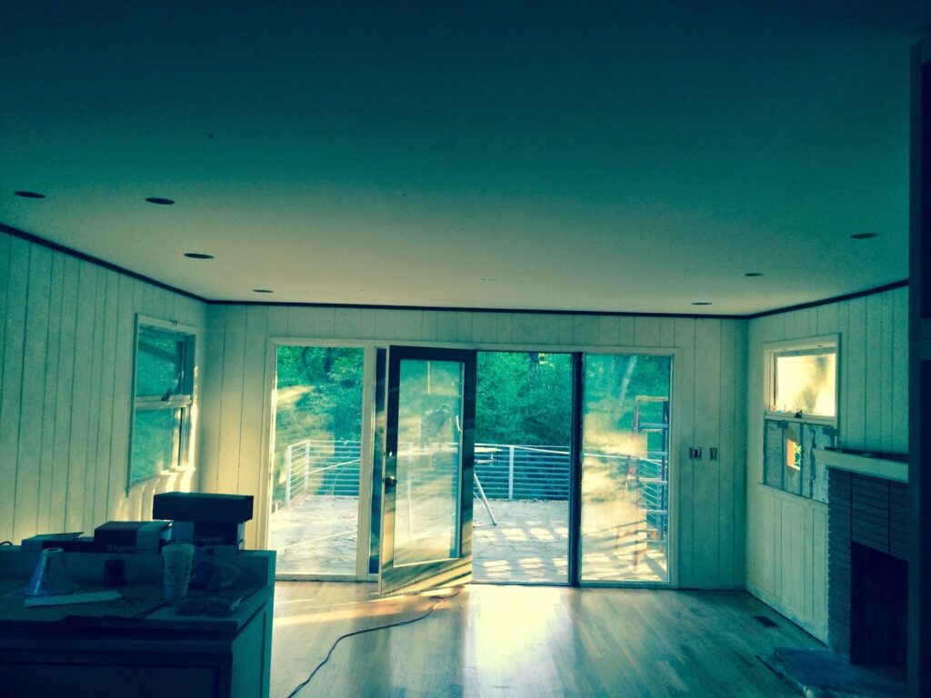 A living room with newly installed recessed lighting and a large sliding glass door by Volt Doctors in Durham, NC