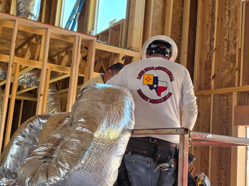 A Lone Star Mechanical technician installing insulated ductwork at a construction site in El Paso, TX.