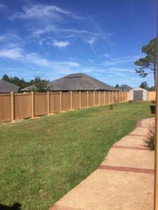 A long, light brown privacy fence installed in a residential backyard by Custom Fence Builders in Gulfport, MS.