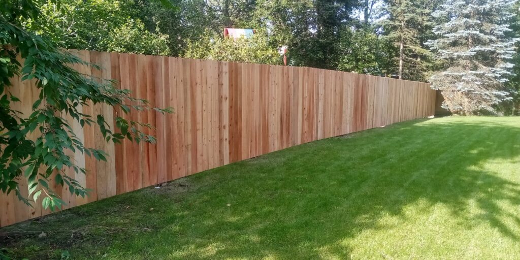 A long, newly installed wood privacy fence defining a backyard boundary, built by Five Star Fence Co. in Anchorage, AK.