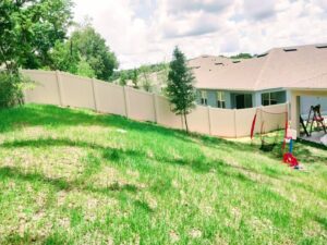 A long beige vinyl fence installed on a sloped residential backyard by Florida Professional Fence LLC in Altamonte Springs, FL.