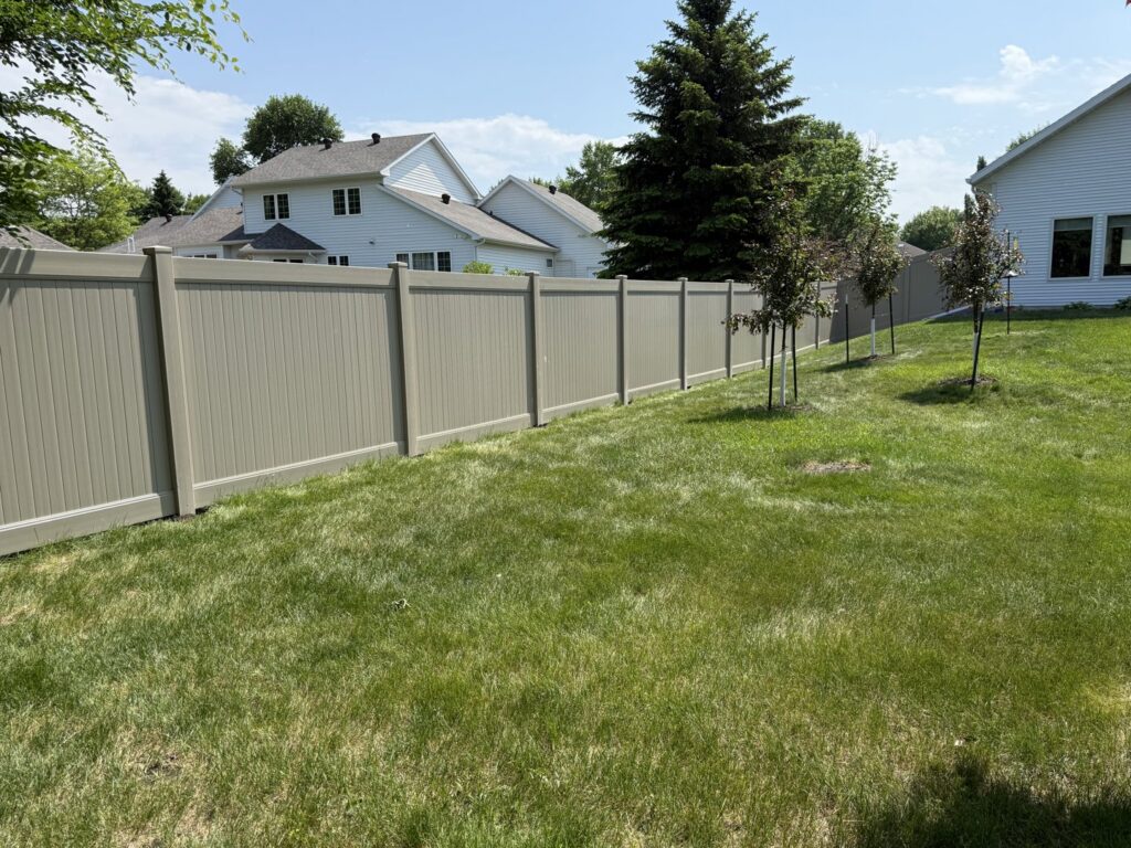A long beige vinyl fence installed in a residential area by Aces Deck and Fence, LLC in Fargo, ND.