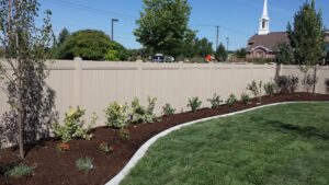 A long beige vinyl privacy fence with new landscaping in front, installed by All American Vinyl in Provo, UT.