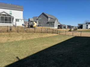 A long section of a newly installed black aluminum fence in a residential backyard by BK FenceWorks in Wentzville, MO.