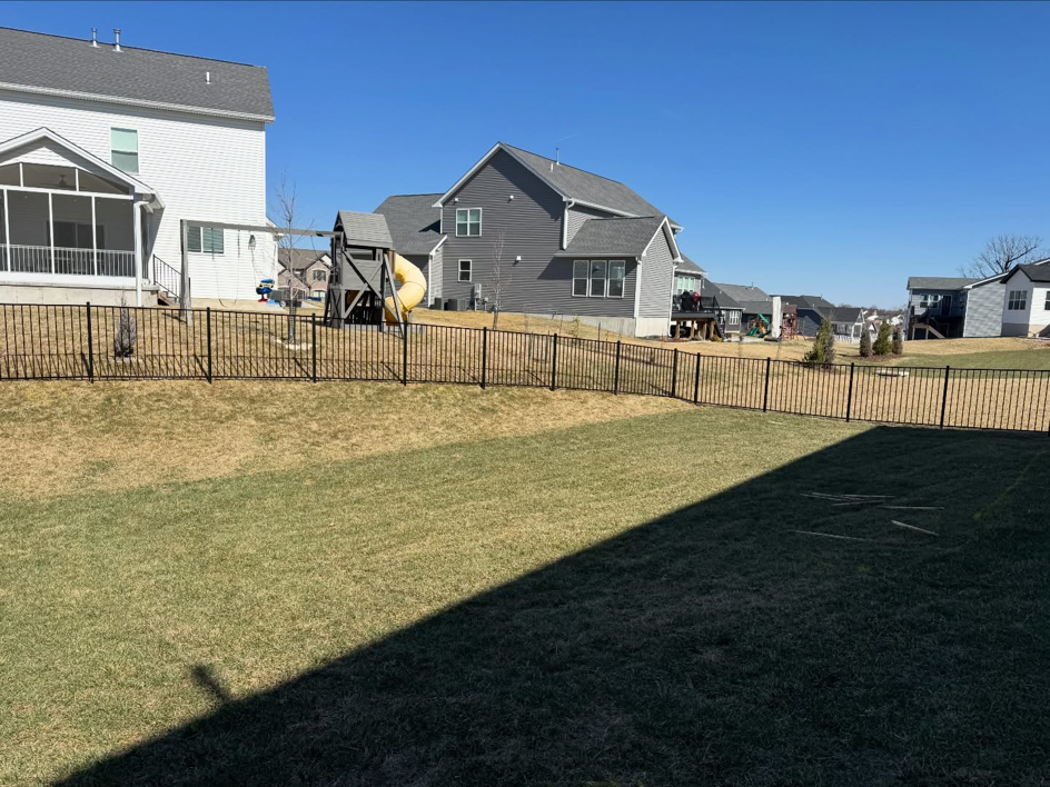 A long section of a newly installed black aluminum fence in a residential backyard by BK FenceWorks in Wentzville, MO.