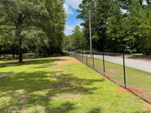 A long black chain link fence installed along a property line by First Class Fence and Landscape LLC in Birmingham, AL.