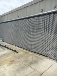A long black chain-link fence installed along a commercial building by Pride Fence LLC in Overland Park, KS.
