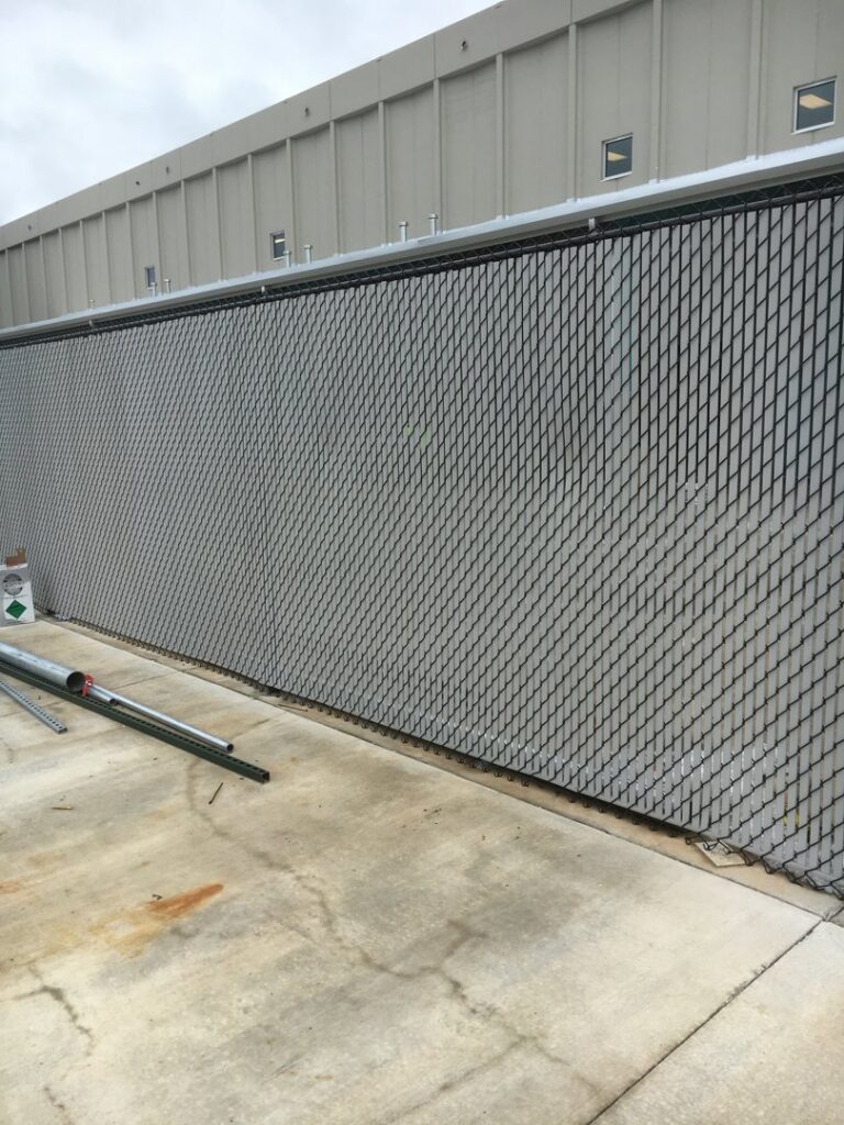 A long black chain-link fence installed along a commercial building by Pride Fence LLC in Overland Park, KS.