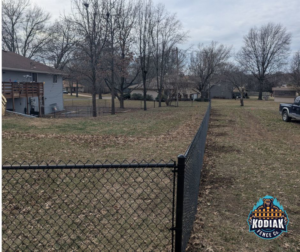 A long stretch of newly installed black chain-link fence by Kodiak Fence Co. in Flower Mound, TX.