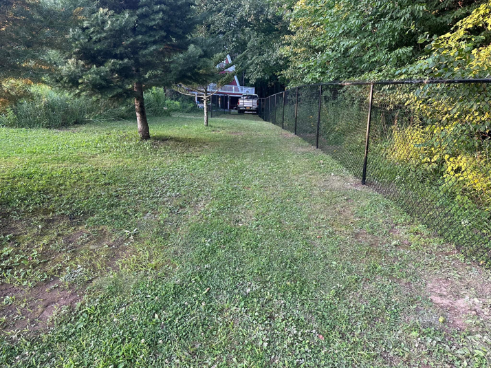 A long stretch of black chain-link fence installed along a grassy property line by Fenced Up, LLC in Ravena, NY.