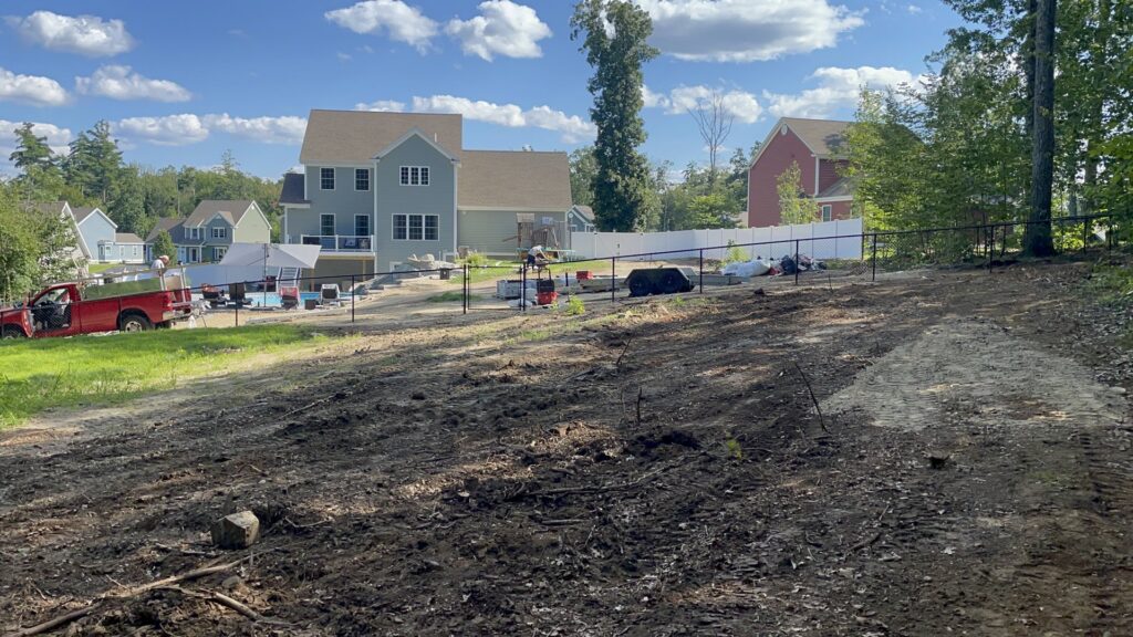 A long black chain-link fence installed on a sloped residential property by Texeira Fencing & Concrete in Springfield, MA.