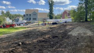 A long black chain-link fence installed on a sloped residential property by Texeira Fencing & Concrete in Springfield, MA.