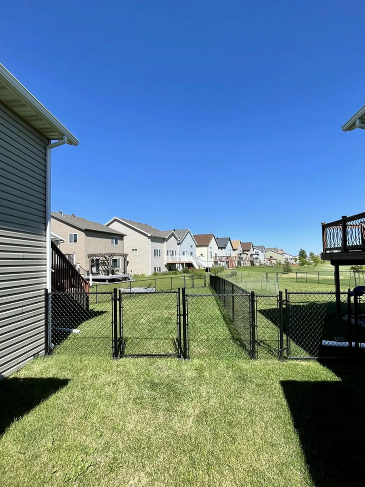 A long black chain-link fence with multiple gates installed in a residential area, providing property division by VASE Construction, LLC in Fargo, ND.