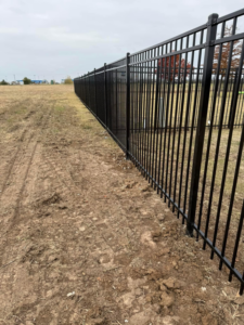 A long black metal fence installation extending into the distance by Goliath Fence Systems and Pre-Stain in Oklahoma City, OK.