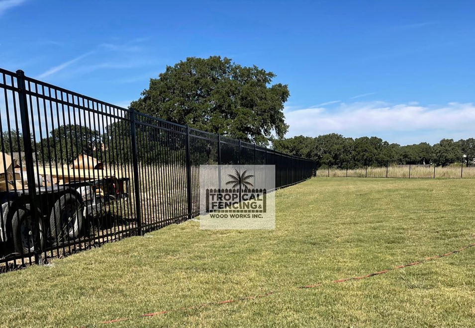 A long black metal perimeter fence installed in a large open area by Tropical Fencing And Wood Works in Page, TX.