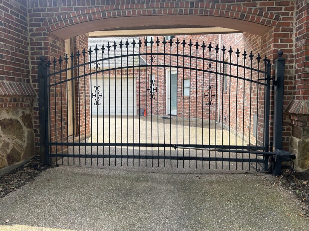 A long black metal security fence with spiked tops installed alongside a roadside by Craftsman Automatic Gates in Dallas, TX