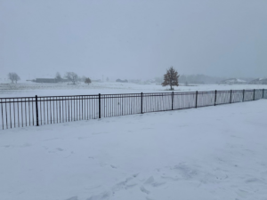 A long black ornamental fence installed across a snowy field by JD Fencing LLC in Boone, IA.