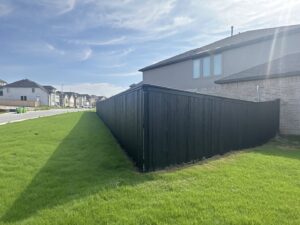 A long black wood privacy fence installed along a residential property by Liberty Fence & Stain in San Antonio, TX.