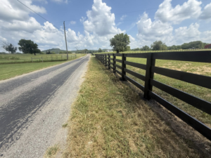 A long black wooden fence installed alongside a rural road by The Fence Painter in Lynnville, TN.