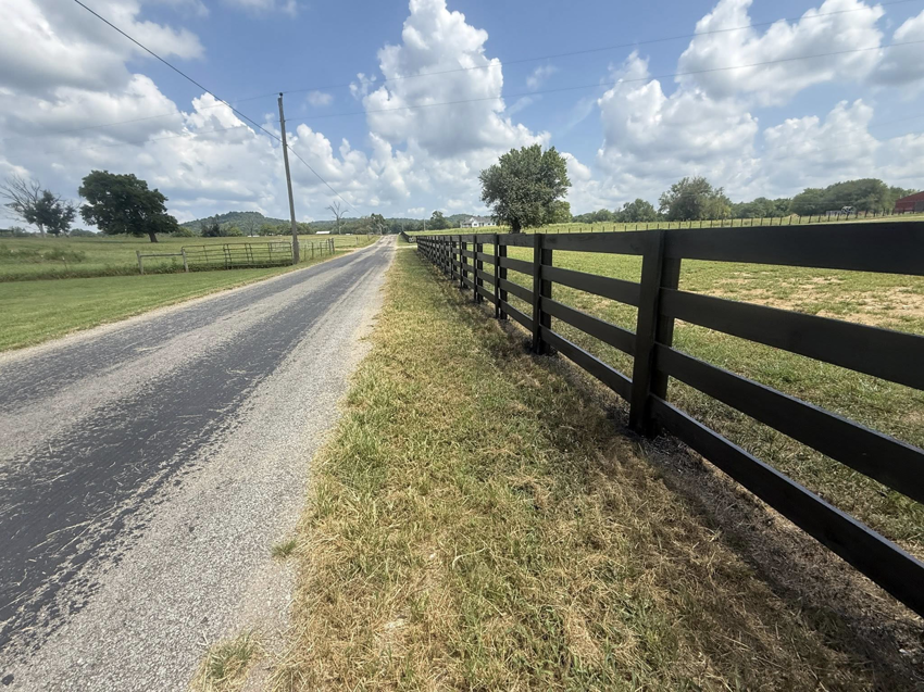 A long black wooden fence installed alongside a rural road by The Fence Painter in Lynnville, TN.
